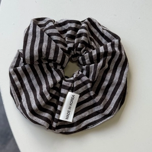 Detailed close-up of a black and grey striped fabric hair scrunchie with a Korea tag