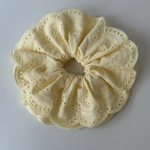 Detail of light yellow lace scrunchie with floral embroidery and scalloped edges