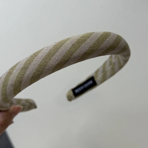 Macro view of olive green striped fabric texture and brand label on wide headband
