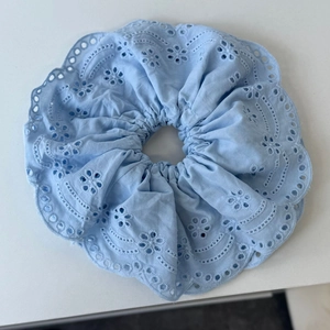 Close-up of light blue cotton scrunchie with intricate floral eyelet embroidery detail