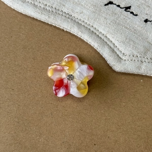Makroaufnahme einer kleinen Blumen-Haarklammer mit Strassstein und Marmorstruktur