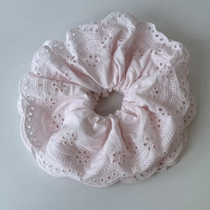 Detail of light pink scalloped scrunchie with delicate floral embroidery and textured fabric