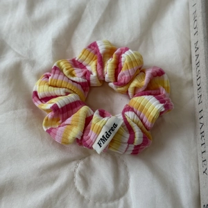 Détail d'un chouchou en tricot à rayures colorées avec texture côtelée et étiquette