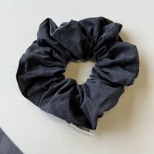 Dettaglio di un elastico per capelli in tessuto a coste grigio scuro con etichetta bianca