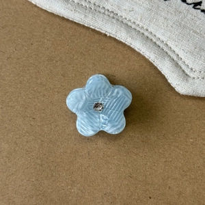 Nahaufnahme der hellblauen Azetat-Blumen-Haarklammer mit Strass und Marmor-Textur