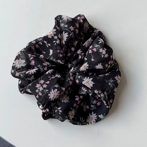 Dettaglio di un elastico per capelli in chiffon con motivo a margherite rosa