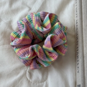 Gros plan sur un chouchou en tricot rayé coloré avec texture côtelée sur tissu blanc