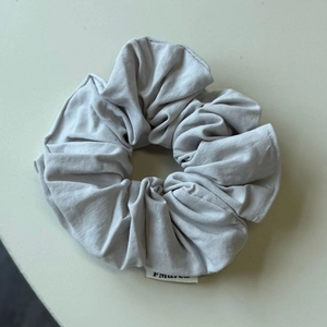 Dettaglio di elastico per capelli in maglia grigio chiaro con trama morbida ed etichetta