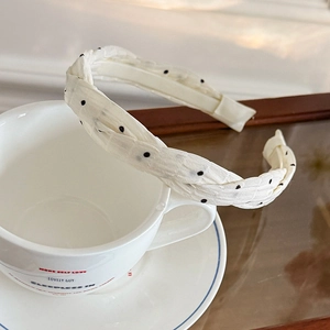 Detailed texture of braided polka dot headband placed on a ceramic coffee cup
