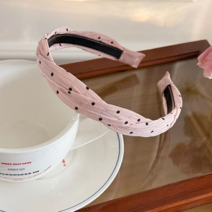 Detailed view of the pink polka dot fabric twist headband with anti-slip inner teeth
