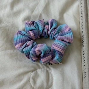 Détail d'un chouchou tricoté à rayures colorées avec petite étiquette tissée sur tissu