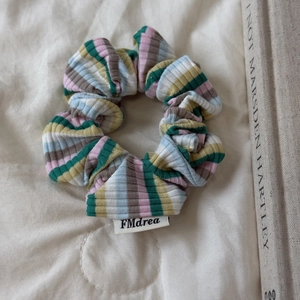 Détail d'un chouchou en maille rayée avec étiquette sur fond de tissu blanc et livre