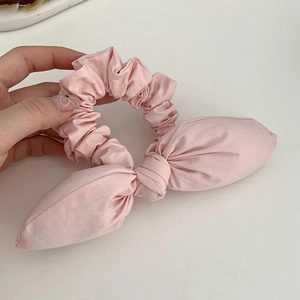 Pink fabric scrunchie with rabbit ear bow design for high ponytail styling
