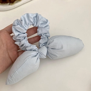 Close-up of light blue fabric hair scrunchie with bunny ear design and soft cotton texture