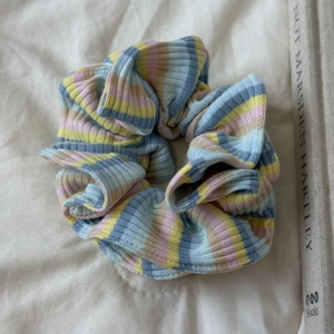 Détail d'un chouchou rayé en maille côtelée colorée aux tons doux rose jaune et bleu