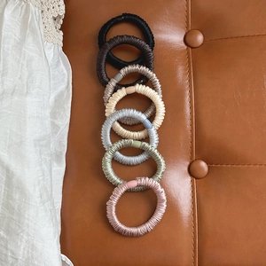 Detail shot of multi-colored pleated satin hair scrunchies on a soft textured background