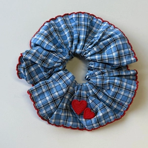 Detail of blue glen plaid scrunchie with red wavy edges and heart embroidery