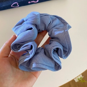 Macro shot of light blue scrunchie showing detailed denim texture and ruffled fabric folds