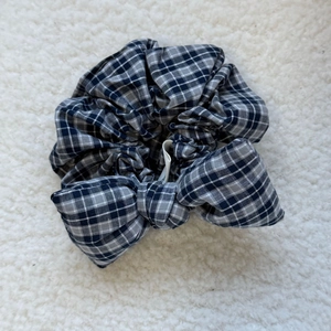 Detail view of a vintage plaid sponge bow scrunchie on a soft textured background