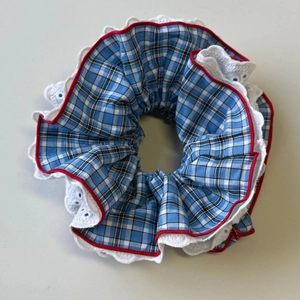 Detail of blue and white plaid scrunchie with lace trim and red piping accents
