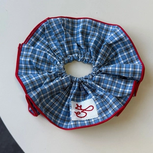 Detail of red and blue plaid scrunchie with cute embroidery and cotton texture