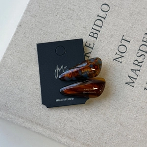 Close-up of tortoise shell acetic acid teardrop hair clips set with gold brand logo lettering