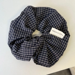 Detail van een Koreaanse haarscrunchie met blauwe ruitjes en geweven stoffen label