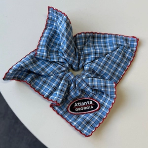 Detail of blue gingham scrunchie with red scalloped edges and Atlanta embroidery