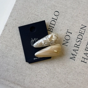 Close-up of teardrop acetate hair clips in marble white and translucent brown colors
