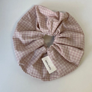 Detailweergave van de roze-wit geruite stoffen scrunchie met handgemaakt geweven label