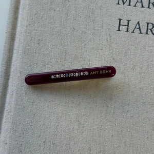 Macro shot of deep purple acetate hair clip with sparkling rhinestones and gold AMY BEAR text