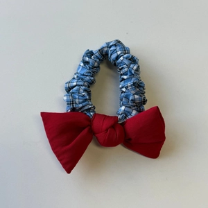 Detail of blue and white checkered scrunchie with a vibrant red bow hair accessory