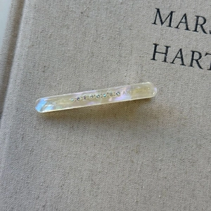 Close-up of iridescent acetate hair clip with sparkling rhinestones and Amy Bear logo