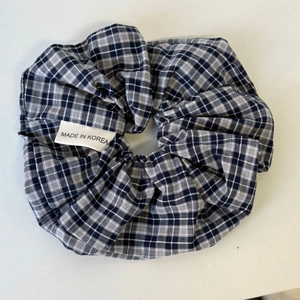 Detail van een klassieke marineblauwe en grijze geruite scrunchie met een label
