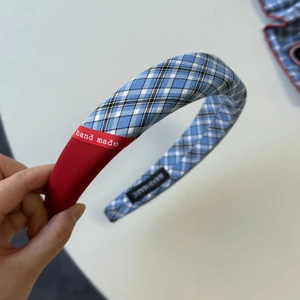 Detail of checkered plaid scrunchie with hand made label and red fabric texture