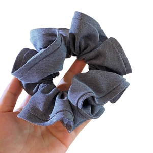 Grey twill fabric oversized scrunchie hair tie held by hand against white background