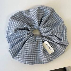 Detailopname van blauw-bruine geruite scrunchie met een handgemaakt stoffen label