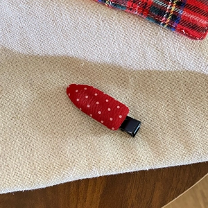 Close-up of red and white polka dot hair clip on a textured fabric background