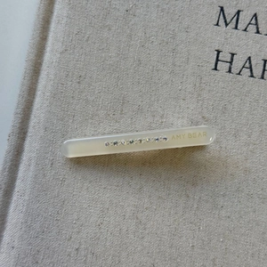 Close-up of cream acetate hair clip with small rhinestones on a linen texture background