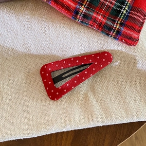 Red and white polka dot fabric wrapped BB hair clip on vintage beige linen background
