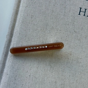 Close-up of amber acetate hair clip with colorful rhinestones and gold engraving
