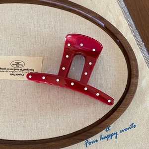 French style red polka dot claw clip hair accessory with white spots on wooden tray