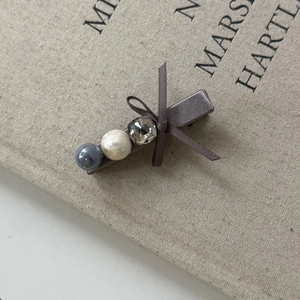 Elegante fermaglio per capelli con fiocco grigio, cristalli e perle su sfondo di libro