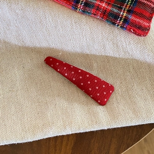 Detail of red fabric hair clip with white polka dots on a natural linen background