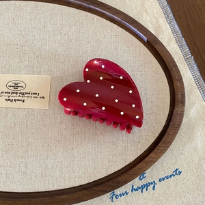 French vintage heart-shaped hair claw with red white polka dot pattern on wooden base