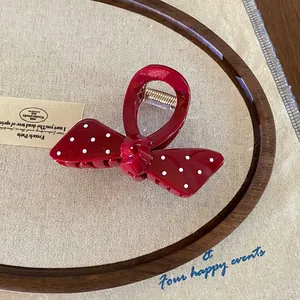 Macro shot of a vintage red polka dot bow hair claw clip on an oval wooden frame