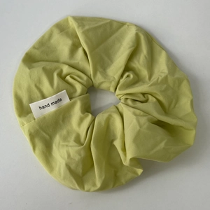 Detailed macro view of a light green fabric scrunchie with handmade woven label