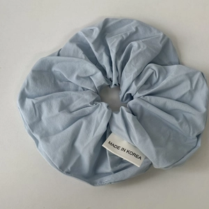 Detail of light blue pleated hair scrunchie with a Made in Korea white fabric label
