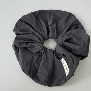 Close-up of a handmade dark grey oversized ruched scrunchie with a woven hand made tag