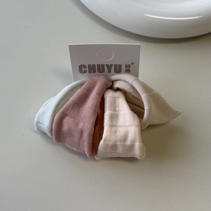 Detail of three textured knit hair ties in Morandi tones on retail display card